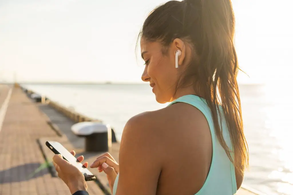 Does Bluetooth Use Data? Woman listening to music on phone with wireless earbuds